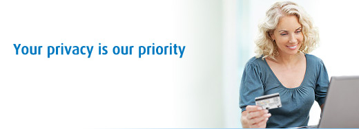 Photo of a woman holding her credit card infront of her computer smiling