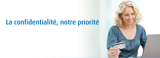 Image d'une femme souriante assise devant son ordinateur et tenant sa carte de crédit en main