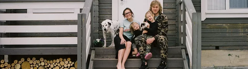 A family sitting on the front stoop of their home.