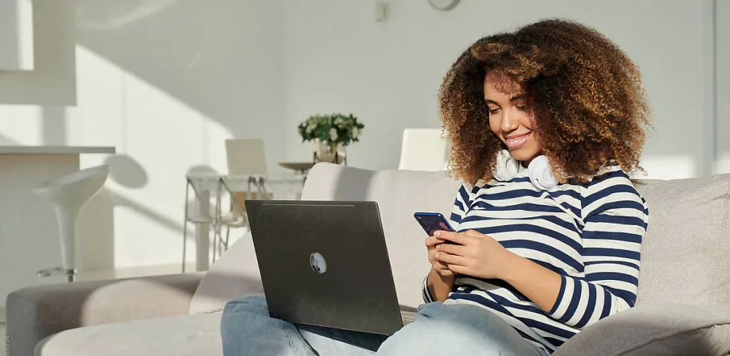 Woman checking phone and on her laptop