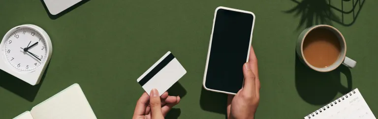 Top down view of a pair of hands holding a credit card and phone