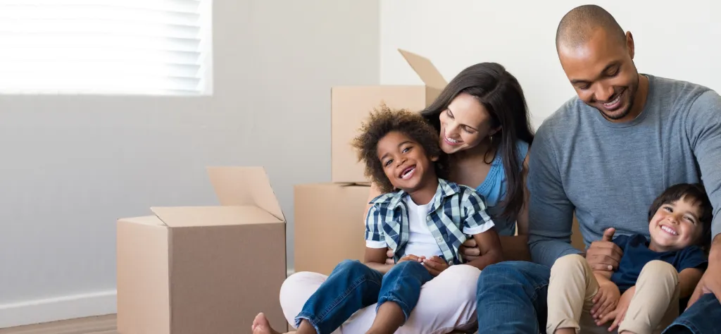 A happy family sits on the floor of their new home