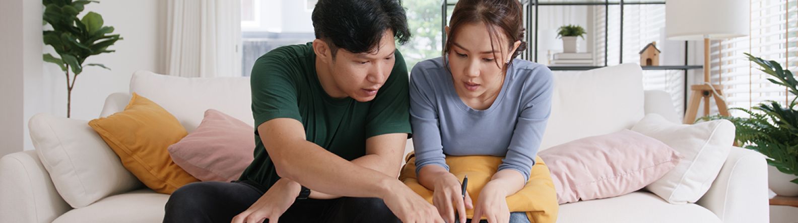 Couple sur un canapé en train de travailler sur un document