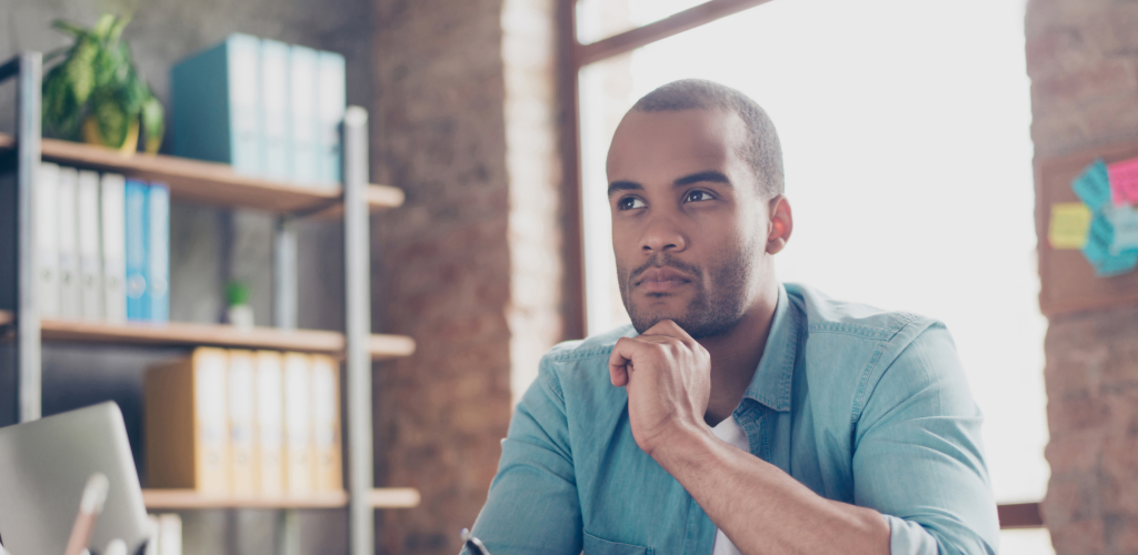 A man sits at a desk and wonders about his financial future