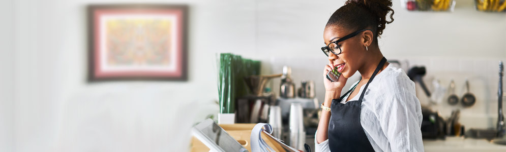 Woman holding cell phone in a cafe background.